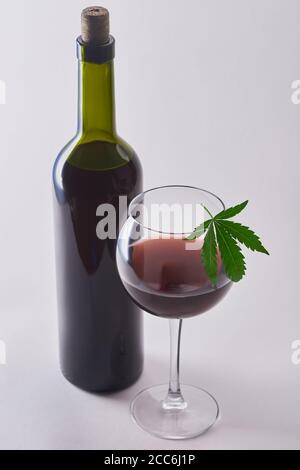 Un verre et une bouteille de vin rouge avec du cannabis perfusion sur fond blanc Banque D'Images