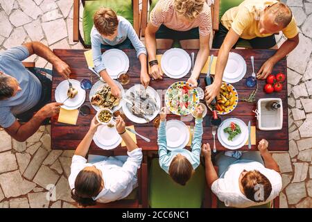 La grande famille a un dîner avec un repas fraîchement cuisiné sur la terrasse du jardin Banque D'Images