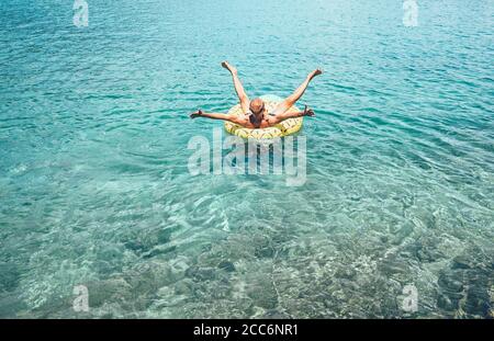 L'homme nage sur l'anneau gonflable de piscine à l'ananas en cristal clair eau de mer Banque D'Images