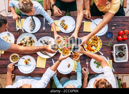 Vue verticale du dessus de la table servie et des mains avec du clinking gobelets Banque D'Images