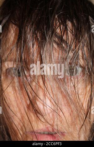 Gros plan sur le visage de la femme en regardant à travers les cheveux mouillés, format vertical Banque D'Images