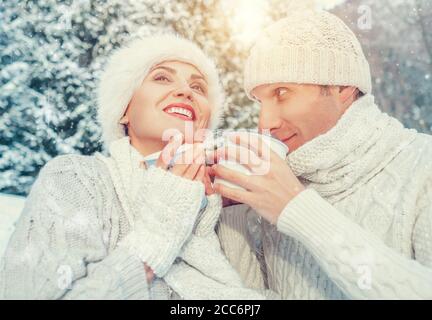 Confortable couple habillé dans l'amour boire chaud de thé dans la forêt d'hiver Banque D'Images