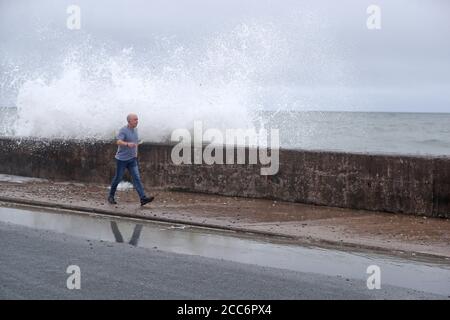 Les gens essaient d'éviter que les vagues ne s'écrasant sur le front Strand à Youghal, Co. Cork. Un avertissement de vent rouge a été émis par met Eireann pour la région, et un avertissement orange a été émis pour Galway, Mayo, Clare, Kerry, Limerick et Waterford, alors que Storm Ellen balaie le pays depuis mercredi soir. Banque D'Images