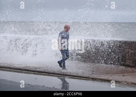 Un homme est frappé par une vague s'écrasant sur le front Strand à Youghal, Co. Cork. Un avertissement de vent rouge a été émis par met Eireann pour la région, et un avertissement orange a été émis pour Galway, Mayo, Clare, Kerry, Limerick et Waterford, alors que Storm Ellen balaie le pays depuis mercredi soir. Banque D'Images