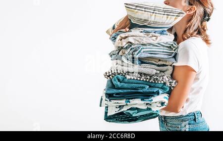 Femme prend dans les mains de grands tas bleu et beige couvertures, serviettes et autres textiles domestiques Banque D'Images