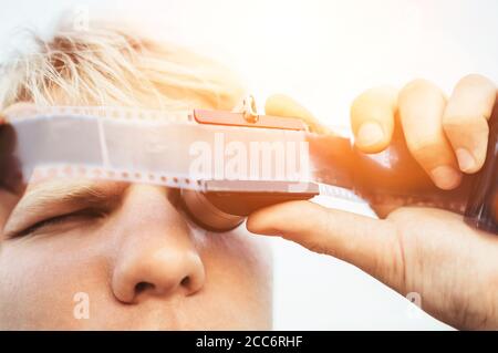 Masculin utilise l'ancien film 35 mm négatif Viewer pour voir un cadre Banque D'Images