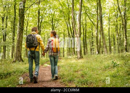 des routards mâles et femelles marchant dans une forêt tenant les mains Banque D'Images