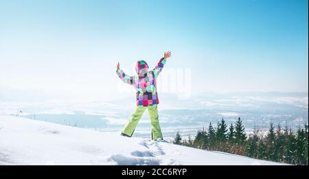 Bonne petite fille sautant sur la colline de neige Banque D'Images