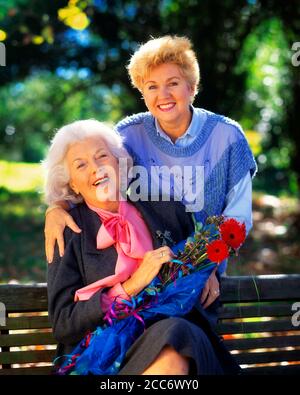 PORTRAIT DES ANNÉES 1990 D'UNE FILLE ADULTE SOURIANTE QUI LUI REVENAIT DES FLEURS MÈRE À L'EXTÉRIEUR LES DEUX REGARDANT LA CAMÉRA - KJ11962 DEG002 HARS PAIRE BEAUTÉ BANLIEUE COULEUR URBAINE SA RELATION MÈRES AÎNÉS TEMPS NOSTALGIE EMBRASSANT LA VIEILLE MODE 1 BOUQUET JEUNE STYLE COMMUNICATION LES GÉNÉRATIONS EMBRASSENT HEUREUX FAMILLES JOIE STYLE DE VIE SATISFACTION CÉLÉBRATION FEMMES AÎNÉES GROGNUP SAINTETÉ COPIE ESPACE PERSONNES ENFANTS AMITIÉ DEMI-LONGUEUR CÂLIN DAMES FILLES PERSONNES INSPIRATION S'OCCUPANT D'UN ADULTE SENIOR EN ÉTÉ CONTACT VISUEL SENIOR FEMME BONHEUR VIEILLESSE OLDSTERS GAI OLDSTER STYLES EXCITATION Banque D'Images