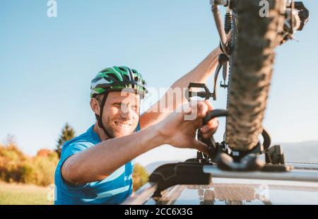 Un motard de montagne tient son vélo sur la voiture toit Banque D'Images