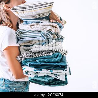 Femme prend dans les mains de grands tas bleu et beige couvertures, serviettes et autres textiles domestiques Banque D'Images