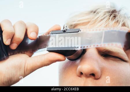 Masculin utilise l'ancien film 35 mm négatif Viewer pour voir un cadre sur les diapositives de l'appareil photo d'époque Banque D'Images