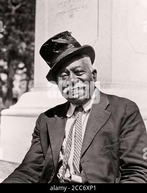 HOMME SENIOR AFRO-AMÉRICAIN SOURIANT DES ANNÉES 1930 PORTANT UN CHAPEAU MANTEAU CRAVATE TOURISTE COACHMAN REGARDANT LA CAMÉRA ST. AUGUSTINE FLORIDA USA - N18 HAR001 HARS ESPACE DE COPIE DEMI-LONGUEUR ÉTATS-UNIS D'AMÉRIQUE CARACTÈRE CONFIANCE HOMME SENIOR TRANSPORT ADULTE SENIOR B&W AMÉRIQUE DU NORD CONTACT OCULAIRE MOUSTACHE NORD-AMÉRICAINE COMPÉTENCE COSTUME ET CRAVATE PROFESSION BONHEUR COMPÉTENCES GAI SERVICE À LA CLIENTÈLE MOUSTACHES AFRO-AMÉRICAINS AFRICAN-AMÉRICAIN TOURISME NOIR ETHNICITÉ FIERTÉ AUTORITÉ CHEVEUX FACIAUX OCCUPATIONS SMILES GUIDE CONCEPTUEL JOYEUSE ET ÉLÉGANTE ST JOVIAL. AUGUSTINE TEAMSTER BATTUE FL NOIR ET BLANC HAR001 Banque D'Images