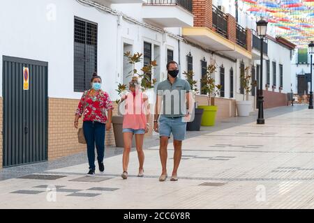 Huelva, Espagne - 15 août 2020: Personnes marchant dans une rue avec des parasols colorés dans le ciel, portant des masques protecteurs à cause de Covid-19. Nouveau normal i Banque D'Images