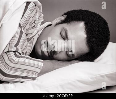 HOMME AFRO-AMÉRICAIN DES ANNÉES 1970 AVEC MOUSTACHE PORTANT UN PYJAMA À RAYURES ENDORMI AU LIT AVEC UNE EXPRESSION DU VISAGE PAISIBLE ET PAISIBLE - S20400 HAR001 HARS SERENITY EXPRESSIONS B&W REPOS MOUSTACHE RÊVES SOMMEIL TÊTE DE BIEN-ÊTRE ET LES ÉPAULES MOUSTACHES AFRO-AMÉRICAINS L'ETHNIE NOIRE AFRO-AMÉRICAINE DANS LE VISAGE D'OCCASION CHEVEUX PAISIBLE CONCEPT ÉCHAPPER ÉLÉGANT REPOSANT AGRÉABLE CROISSANCE DÉTENTE REPOS BIEN-ÊTRE JEUNE HOMME ADULTE NOIR ET BLANC HAR001 ANCIEN LES AFRO-AMÉRICAINS À LA MODE Banque D'Images