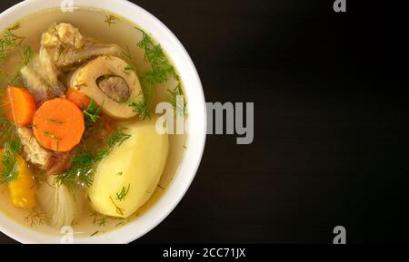 Soupe Shurpa dans un bol blanc sur fond de bois foncé avec espace de copie. Vue de dessus. Célèbre soupe traditionnelle asiatique, ouzbek, Moyen-Orient avec du bœuf ou de l'agneau Banque D'Images