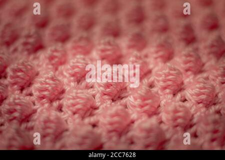 Fond rose texturé composé d'une couverture de bébé crochetée en fil rose dans le point de galet également connu comme le point d'ananas Banque D'Images