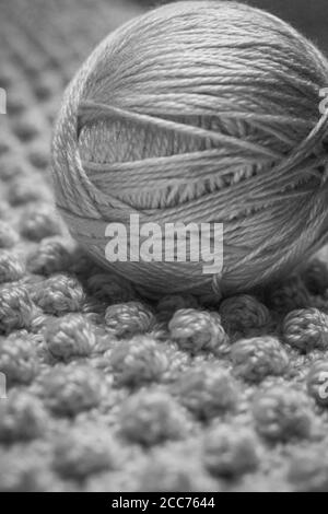 Photographie en noir et blanc d'une balle de fil avec arrière-plan texturé composé d'une couverture de bébé crochetée dans le galet point également connu sous le nom de pin Banque D'Images