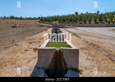 L'eau s'écoule du ressort vers les creux animaux en béton aligné l'un derrière l'autre Banque D'Images
