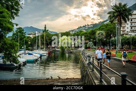 Locarno Suisse , 1er juillet 2020 : personnes sur la promenade de Locarno sur les rives du lac majeur au coucher du soleil avec vue sur le port de plaisance de Locarno Tessin Suisse Banque D'Images