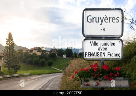 Panneau Gruyères à l'entrée de la ville et du village médiéval en arrière-plan à Gruyères Suisse ( traduction : jumelé avec Renaison France ) Banque D'Images
