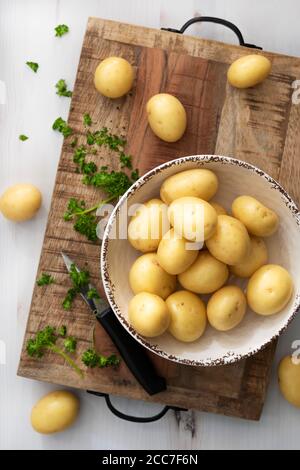 Bol de pommes de terre blanches et de persil haché sur une planche à découper en bois. Banque D'Images
