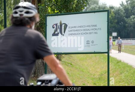 18 août 2020, Saxe-Anhalt, Wörlitz : un visiteur du Royaume des jardins de Wörlitz passe son vélo devant un panneau. Il y a 20 ans, les parcs près de Dessau ont été reconnus comme patrimoine culturel mondial. Photo: Sebastian Willnow/dpa-Zentralbild/dpa Banque D'Images