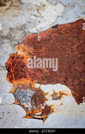 Vue abstraite de la peinture au plomb écaillée sur une surface métallique très rouillée; couleurs bleu, orange et rouge Banque D'Images