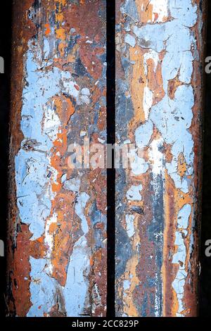 Vue abstraite de la peinture au plomb écaillée sur une surface métallique très rouillée; couleurs bleu, orange et rouge Banque D'Images