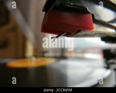 Gros plan du stylet du tourne-disque et prise en main avec le disque vinyle doux focalisé en arrière-plan Banque D'Images