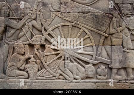 Cambodge: Dans le camp de l'armée khmère, un homme souffle sur un feu pour cuire de la nourriture à côté d'une charrette, du mur oriental du bas-relief, de la section sud, du Bayon, d'Angkor Thom. Le Bayon était à l'origine le temple officiel du roi bouddhiste Mahayana Jayavarman VII Le Bayon, au centre d'Angkor Thom (Grande ville), fut fondé au XIIe siècle par le roi Jayavarman VII Angkor Thom, signifiant "la Grande ville", est situé à un mile au nord d'Angkor Wat. Il a été construit à la fin du XIIe siècle ce par le roi Jayavarman VII Banque D'Images