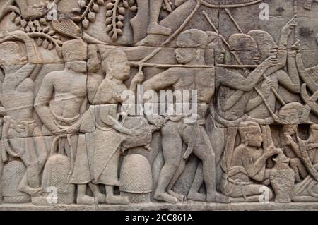 Cambodge: Une femme secoue une tortue dans le fond d'un soldat en lui donnant un choc alors que l'armée khmère avance, le bas-secours mur de l'est, la section sud, le Bayon, Angkor Thom. Le Bayon était à l'origine le temple officiel du roi bouddhiste Mahayana Jayavarman VII Le Bayon, au centre d'Angkor Thom (Grande ville), fut fondé au XIIe siècle par le roi Jayavarman VII Angkor Thom, signifiant "la Grande ville", est situé à un mile au nord d'Angkor Wat. Il a été construit à la fin du XIIe siècle ce par le roi Jayavarman VII Banque D'Images