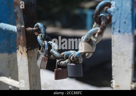 Plusieurs cadenas pendent d'une ancienne chaîne. Cadenas de mariage enchaînés au pont de la ville. Symbole de l'amour et de la tradition de mariage ancienne. Vieux rouillé chéri l Banque D'Images