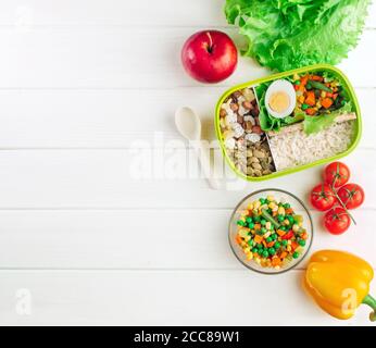 Boîte à lunch remplie de riz et de légumes mélangés sur blanc arrière-plan en bois avec espace de copie Banque D'Images