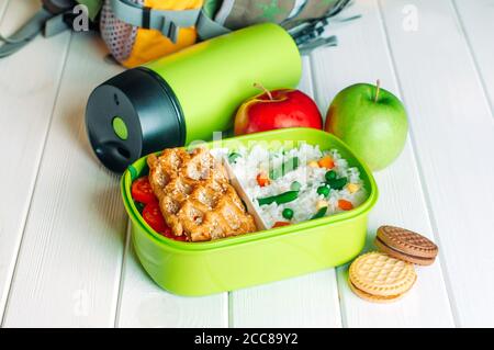 Panier repas près des thermos, des pommes fraîches et des biscuits devant le sac à dos de l'école Banque D'Images