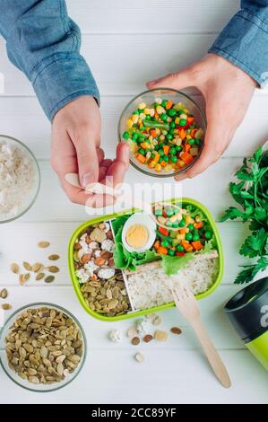 Les hommes ont rempli les mains de la boîte à lunch avec des légumes mélangés sur blanc arrière-plan Banque D'Images