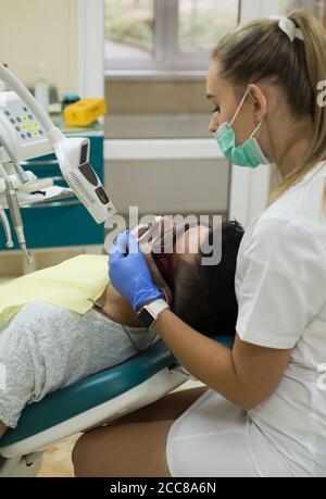 Jeune homme choisissant la couleur des dents chez le dentiste, gros plan. Homme barbu ayant des dents examinées chez des dentistes. Homme âgé ayant un traitement dentaire chez le dentiste Banque D'Images