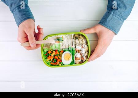 Les hommes tiennent la boîte à lunch pour manger du riz, des légumes mélangés, des œufs durs Banque D'Images