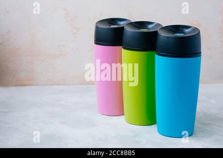 Trois mugs thermos en plastique sur fond gris avec copie espace Banque D'Images