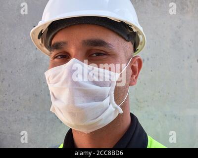L'ingénieur civil porte un masque médical de protection contre un mur en béton sur le chantier de construction. Banque D'Images
