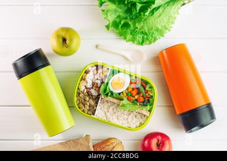 Vue de dessus de la boîte à lunch et de deux tasses thermos arrière-plan en bois clair Banque D'Images