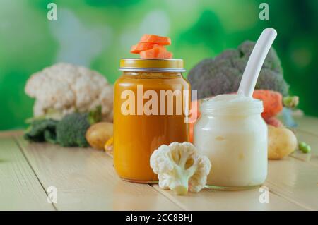 Deux pots de purée de carottes, de potiron et de chou-fleur près des légumes frais Banque D'Images