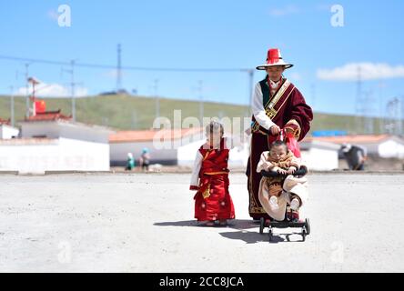 (200820) -- GOLOG, le 20 août 2020 (Xinhua) -- Villager Lhamo fait une promenade avec son fils et sa fille dans le village de Ghadan du canton de Machali, comté de Madoi, préfecture autonome tibétaine de Golog, province de Qinghai, dans le nord-ouest de la Chine, le 19 août 2020. En octobre 2018, un total de 1,036 000 résidents recensés, victimes de la pauvreté, ont déménagé des terres moins hospitalières du comté de Madoi à Ghadan, un village de réinstallation récemment construit dans la région source de la rivière Yellow. Le nouveau village dispose d'un meilleur transport, ce qui permet aux villageois de trouver plus facilement des emplois ou de démarrer des entreprises dans d'autres villes. Pendant ce temps, beaucoup de villageois Banque D'Images