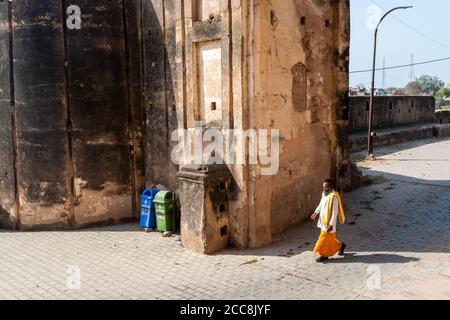 Orcha, Madhya Pradesh, Inde - Mars 2019: Un ermite indien en tenue traditionnelle marchant le long des anciens murs altérés du fort Orcha. Banque D'Images