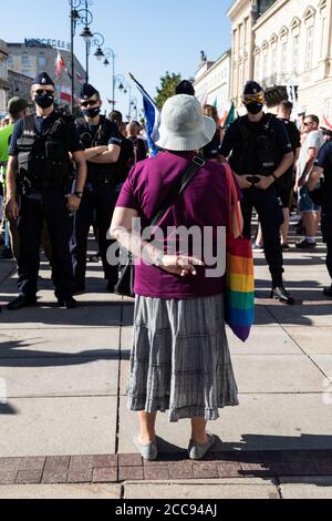 Vieille femme avec sac LGBT arc-en-ciel debout devant police Banque D'Images