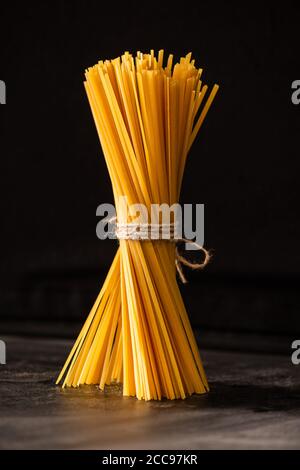 Spaghetti italiens non cuits attachés isolés sur du noir Banque D'Images