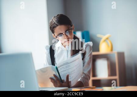 Brunette fille en lunettes de vue lisant un rapport et regardant impliqué Banque D'Images