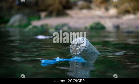 Coronavirus polluant l'environnement. Les vagues délavent les vieux déchets de masque médical, bouteille en plastique et gants. Les équipements de protection entrent dans le wat Banque D'Images