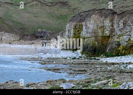 Hautes falaises de craie, gens et chiens, plage de crique rocheuse, rochers sur la mer, mer calme, pillote de la Seconde Guerre mondiale - Thornwick Bay Flamborough, côte est du Yorkshire, Angleterre Banque D'Images