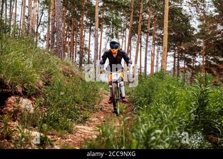 un athlète de descente pilote fait une course sur piste dans la forêt de pins Banque D'Images